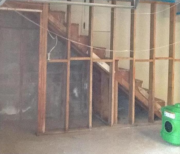 Wall removed down to framing with green SERVPRO equipment in corner