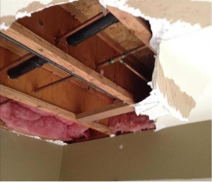 Ceiling with pieces missing exposing insulation and wood beams
